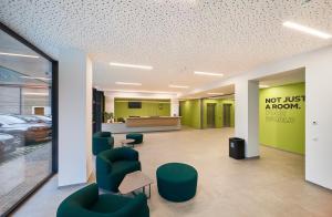 Die Eingangshalle eines Krankenhauses mit grünen Stühlen und einem Wartezimmer in der Unterkunft Ferrari Tower in Bozen