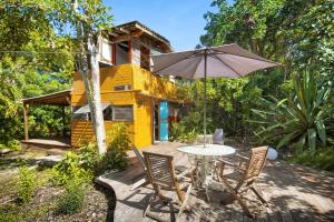 a yellow house with a table and chairs and an umbrella at Esprit Caraibe in Saint-François