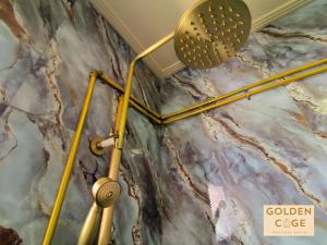 a shower in a room with a marble wall at Golden Cage Heritage Hostel in Denpasar