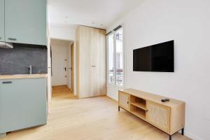a kitchen with a refrigerator and a tv on a wall at Charming studio for 2P - near Parc Monceau in Paris