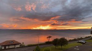 a sunset over a road with a house and the ocean at View of the Isles 2 in Largs