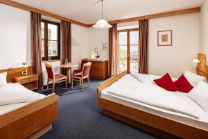 a hotel room with two beds and a table and chairs at Kalterer See Hof in Caldaro