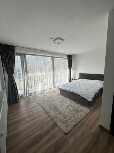 a white bedroom with a bed and a large window at Casa Montwis in Brezoi +16 photos