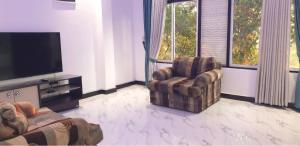 a living room with a chair and a flat screen tv at Sevmeth Villa in Kandy