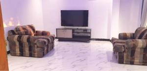a living room with two chairs and a flat screen tv at Sevmeth Villa in Kandy