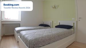 two beds in a white bedroom with a window at Asiago Millepini in Asiago