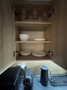 a cupboard with plates and wine glasses in it at Apartment MBD in Veľká Mača +18 photos