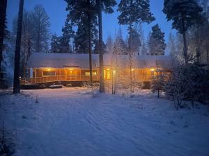 a building in the snow at night with lights at Pinewood Guesthouse in Mäntsälä