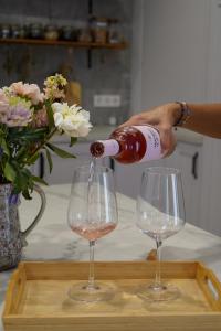 a person pouring a bottle of wine into two wine glasses at Hearts & Home in Mijas