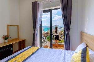 a woman is looking out the window of a bedroom at Hanah Hotel Phan Thiet in Phan Thiet +24 photos