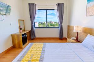 a bedroom with a bed and a large window at Hanah Hotel Phan Thiet in Phan Thiet