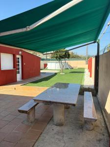 a picnic table with a green awning on a patio at La calma de Aisheric in Nigrán