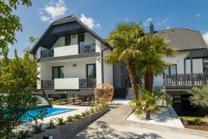 a house with a pool and a palm tree at Boutique Villa Vanilla in Csopak