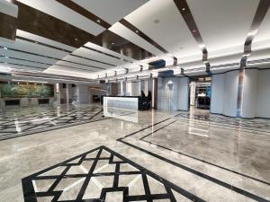 a large room with a lobby with a painting on the wall at Grace Hotel in Bangkok