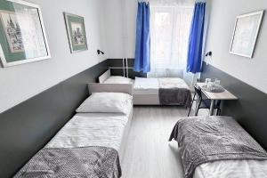 a room with two beds and a table and a window at Dominik Panzió in Budapest