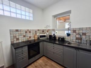 a kitchen with a sink and a microwave at SZEDERMÁLNA Vendégház in Sárospatak