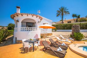 a patio with chairs and a table and an umbrella at Villa La Paz by Abahana Villas in Calpe