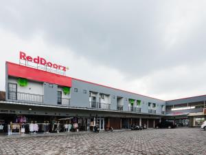 a building with a red brown sign on top of it at RedDoorz Plus Ciapus Bogor in Cimanglid
