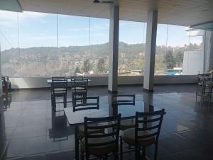 a room with tables and chairs and a large window at Hotel Ratnouday in Kāndi