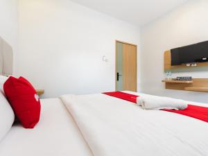 a bedroom with a large white bed with red pillows at RedDoorz Plus Ciapus Bogor in Cimanglid