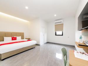 a bedroom with a large bed and a kitchen at RedDoorz Plus Ciapus Bogor in Cimanglid +31 photos