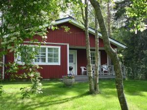 a red house with a porch and chairs in the yard at Strandkulla in Pjelax