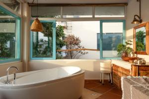 a bathroom with a tub and two windows at Êlim House in Phú Quốc