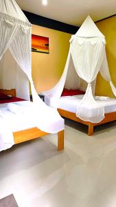 two beds with mosquito nets in a room at Nirvana bungalow's in Boras