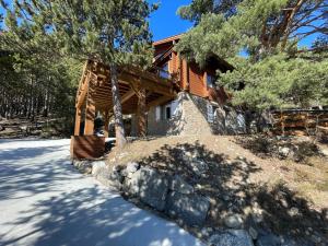 a log cabin with a stone wall in front of a house at Le Chalet aux Biches in Bolquere Pyrenees 2000