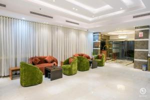 a lobby with green chairs and tables and curtains at فندق امضاء النزيل المدينة المنورة in Medina +84 photos