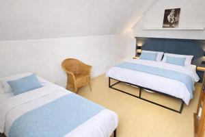 a bedroom with two beds and a chair at Das blaue Haus - Huize Hubertus in Sankt Andreasberg