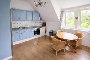 a kitchen with blue cabinets and a table and chairs at Das blaue Haus - Huize Hubertus in Sankt Andreasberg +18 photos