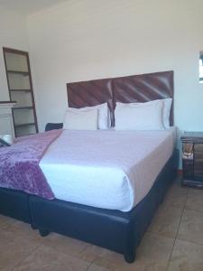 a bedroom with a large bed with a wooden headboard at Duminy Guesthouse in Bellville