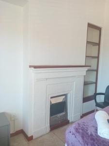 a living room with a white fireplace and a bed at Duminy Guesthouse in Bellville