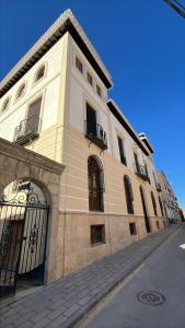 a white building with windows and a gate on a street at Almaterra Apartamentos Turísticos in Huéscar