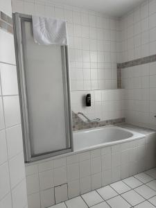 a bath tub in a bathroom with a mirror at Hotel und Restaurant Hohe Schule in Herborn