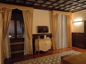 a living room with a television and curtains at Villa Alliata Relais & Spa in Palermo