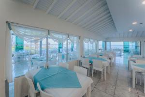 a dining room with tables and chairs and windows at RA Resort Otel in Küçükkuyu