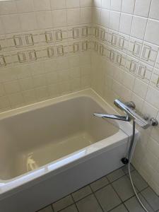 a bath tub with a hose in a bathroom at 古民家宿誠makoto in Tamano +40 photos