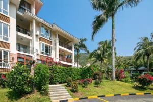 a building with a palm tree and flowers at Yalong Sea Joy in Sanya