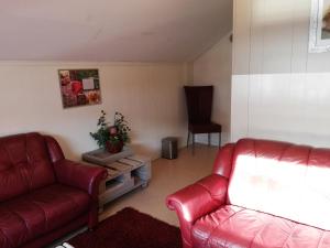a living room with two red couches and a chair at Løvheim Gjestehus in Sauland