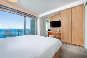 a bedroom with a large bed and a view of the ocean at Kos Aktis Art Hotel in Kos