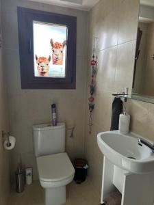a bathroom with a toilet and a sink and a picture of cows at Garden Suite Vila Girasoles in Cálig