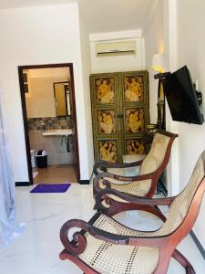 a living room with three chairs and a television at The Villa Hotel in Unawatuna