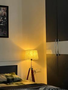 a bedroom with a lamp next to a bed at The Cozy Nest in Gurgaon
