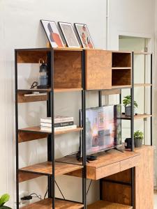 a bookcase with wooden shelves and a tv at Airport Cozy House - Suvarnabhumi in Samutprakarn