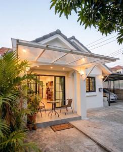 a small white house with a patio with a table at Airport Cozy House - Suvarnabhumi in Samutprakarn
