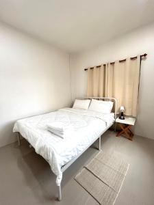 a white bed in a white room with a window at Airport Cozy House - Suvarnabhumi in Samutprakarn