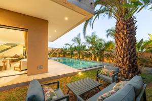 a house with a swimming pool and a palm tree at Villa Capella heated pool and cooker in Marrakesh