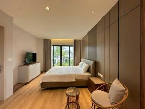 a bedroom with a bed and a tv and a chair at V3K05A Sonasea Vân Đồn in Quang Ninh